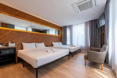 a hotel room with two beds and a chair at Boxpackers Pratunam in Bangkok