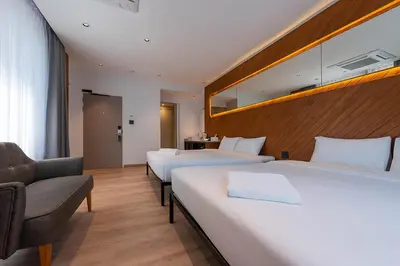 a hotel room with two beds and a chair at Boxpackers Pratunam in Bangkok