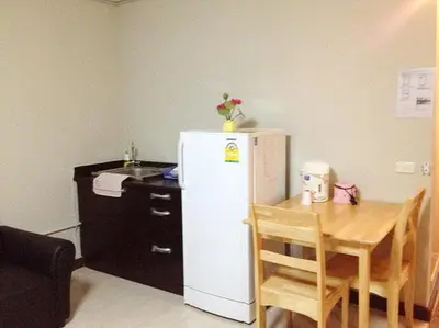 a kitchen with a small table and a white refrigerator at SK Muang Thong Thani in Bangkok