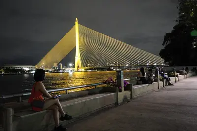 a group of people sitting on benches looking at a bridge at Wild Orchid Villa Bangkok in Bangkok