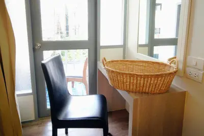 a black chair and a basket in a room with windows at Wild Orchid Villa Bangkok in Bangkok