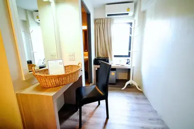 a room with a chair and a mirror and a desk at Wild Orchid Villa Bangkok in Bangkok