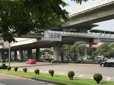 a red car driving down a street under a bridge at T1 Large Studio Full kitchen 100m. to BTS in Bangkok