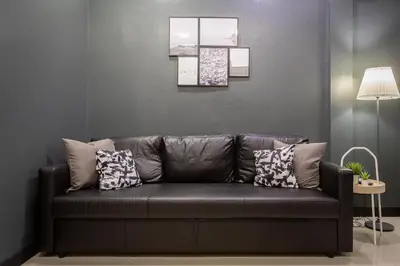 a black leather couch in a living room with pillows at T5 2 Bedrooms/6guests/full kitchen/1 min to BTS in Bangkok