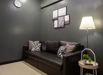 a living room with a black couch and a clock at T5 2 Bedrooms/6guests/full kitchen/1 min to BTS in Bangkok