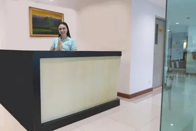 a woman standing behind a counter in a building at The Willing Hotel and Residence in Lak Si