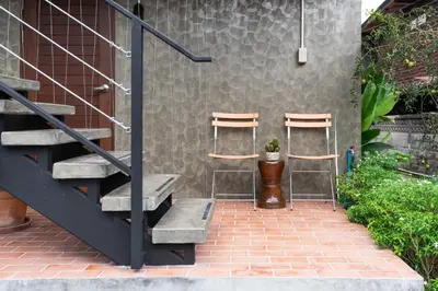 two stools sitting next to a wall with a staircase at Baan Boon in Bangkok