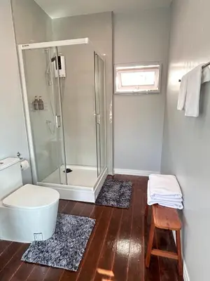 a bathroom with a shower and a toilet and a stool at Baan Boon in Bangkok