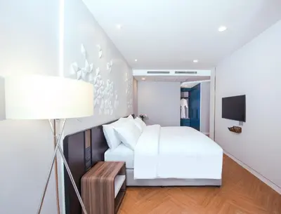 a bedroom with a white bed and a lamp at Amanta Hotel & Residence Sathorn in Bangkok