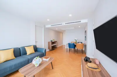 a living room with a blue couch and a flat screen tv at Amanta Hotel & Residence Sathorn in Bangkok