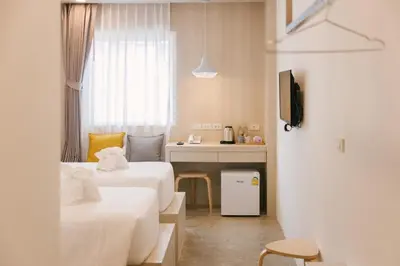 a hotel room with two beds and a desk at Nappiness Hotel in Bangkok