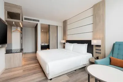 a bedroom with a white bed and a blue chair at Solaria Nishitetsu Hotel Bangkok in Bangkok