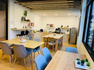 a kitchen and dining room with tables and chairs at Daraya Hostel in Bangkok