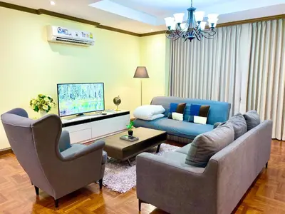 a living room with two chairs and a couch and a tv at NT Place Sukhumvit Suites in Bangkok