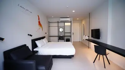 a bedroom with a bed and a couch and a television at CHERN Bangkok in Bangkok