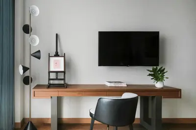 a desk with a television on a wall with a chair at Kimpton Maa-Lai Bangkok by IHG in Bangkok