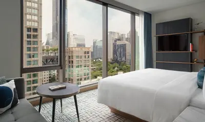 a hotel room with a bed and a large window at Kimpton Maa-Lai Bangkok by IHG in Bangkok