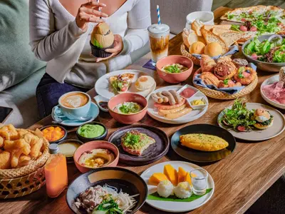 two people sitting at a table with plates of food at Kimpton Maa-Lai Bangkok by IHG in Bangkok