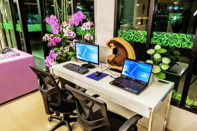 two computers on a desk with chairs and flowers at D Day Suite in Bangkok