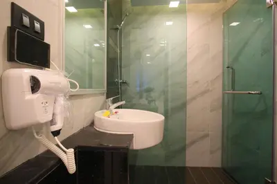 a bathroom with a shower and a sink and a phone at Pratunam Atrium Hotel in Bangkok