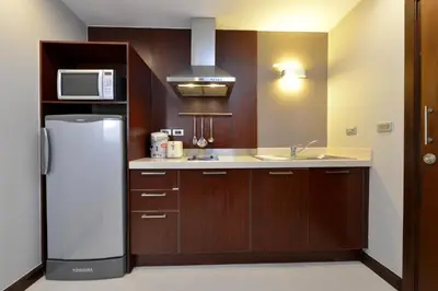 a kitchen with a refrigerator and a microwave at Grand Asoke Suites Boutique Residence in Bangkok