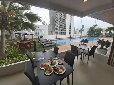 a table with plates of food on a balcony with a pool at Grand Asoke Suites Boutique Residence in Bangkok