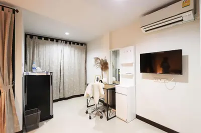 a room with a desk and a tv on a wall at Baanrao Bangson in Bangkok