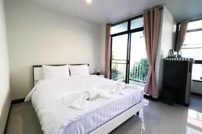 a bedroom with a white bed and a large window at Baanrao Bangson in Bangkok