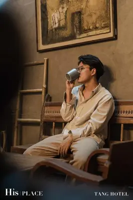 a man sitting in a chair with a cup in his mouth at Tang House in Bangkok