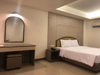 a hotel room with a bed and a mirror at Lee Garden Bangkok in Bangkok