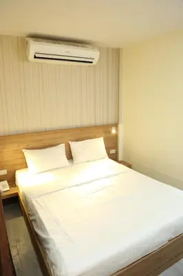 a bedroom with a large white bed with a fan at Rose Nana Hotel in Bangkok
