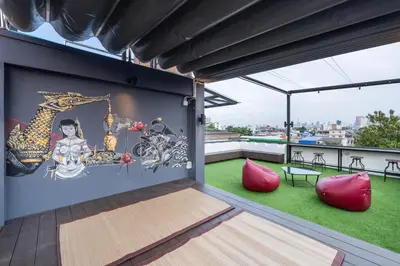 a balcony with red chairs and a painting on the wall at LOBSUEK Hostel in Bangkok