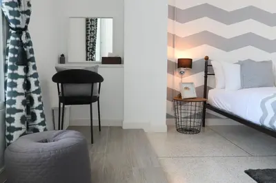 a bedroom with a bed and a chair and a table at Airee Premier Residence in Bangkok