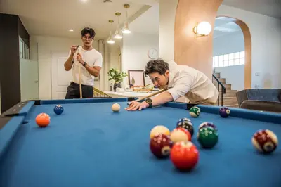 two men playing pool in a living room at Theme Boutique Hotel Bangkok in Bangkok