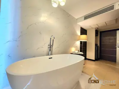 a bath tub in a bathroom with a white wall at Sky dome resotel - โรงแรมสกายโดม รีโซเทล in Bangkok