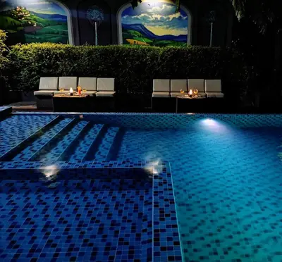 a swimming pool with two benches and lights next to it at Sky dome resotel - โรงแรมสกายโดม รีโซเทล in Bangkok