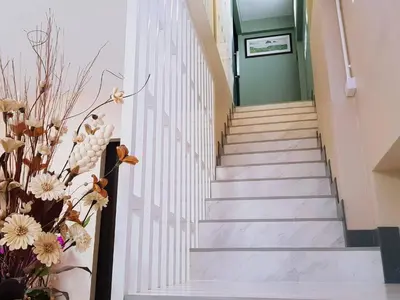 a staircase in a building with a green door and flowers at Baan U-Sabai บ้านอยู่สบาย in Bangkok
