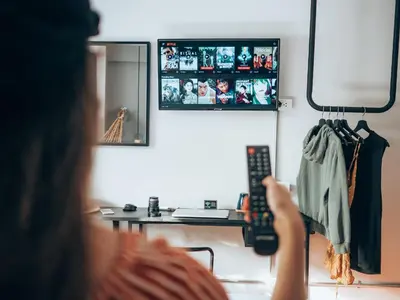 a woman holding a remote control in front of a mirror at Haus Sathorn 11 Residence in Bangkok