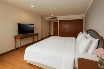 a bedroom with a white bed and a flat screen tv at Rembrandt Residences Bangkok in Bangkok