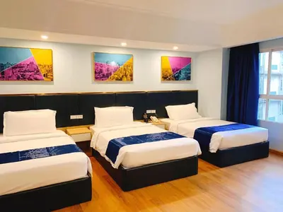 a room with three beds and paintings on the wall at Sapphire Hotel Silom Bangkok in Bangkok