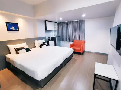 a hotel room with a large bed and a red chair at Star Sukhumvit in Bangkok