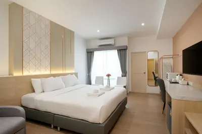 a hotel room with a bed and a desk at Riski Residence Ngamwongwan in Nonthaburi