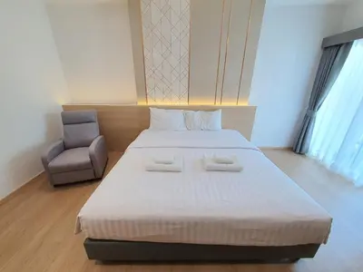 a bedroom with a large bed and a chair at Riski Residence Ngamwongwan in Nonthaburi
