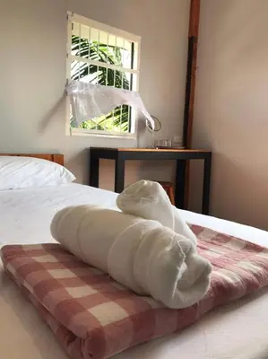 a white towel laying on a bed with a window at BAANYA HOMESTAY Ko Kret in Nonthaburi