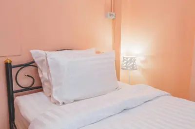 a bed with white pillows on top of it at Gaiwandhanat Homestay in Bangkok