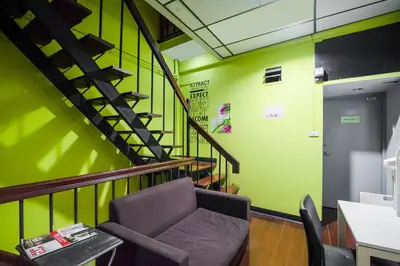 a room with a chair and a staircase with green walls at Ali Hostel in Bangkok