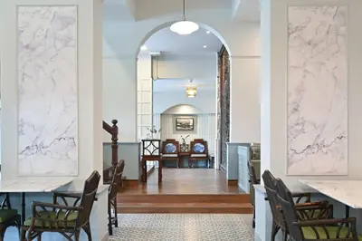 a dining room with white marble walls and a table at The Krungkasem Srikrung Hotel in Bangkok
