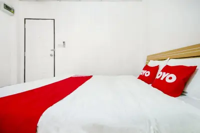 a white bedroom with red pillows on a bed at OYO 525 MRT Phetkasem 48 -1 Place in Bangkok