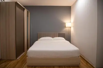 a bedroom with a bed with white sheets and a lamp at J & L Residence and Spa in Ban Khlong Khwang Klang