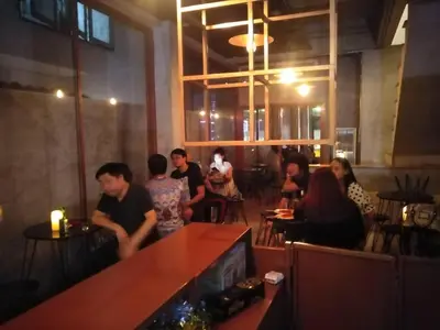a group of people sitting at a bar in a restaurant at Ratchada Hotel - ROTFAI in Bangkok